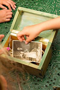 Kinderhände untersuchen ein altes Foto in einer Kiste