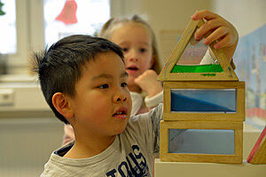 Ein Kind forscht mit Wasser in geometrischen Behältern