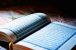 Ein aufgeschlagener Koran auf einer bunten Decke