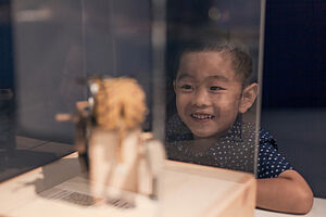 Ein Junge schaut in einem Museum durch eine Vitrine ein Kunstobjekt an