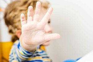 Ein Kind hält die Hand nach vorne und signalisiert so: Stopp.